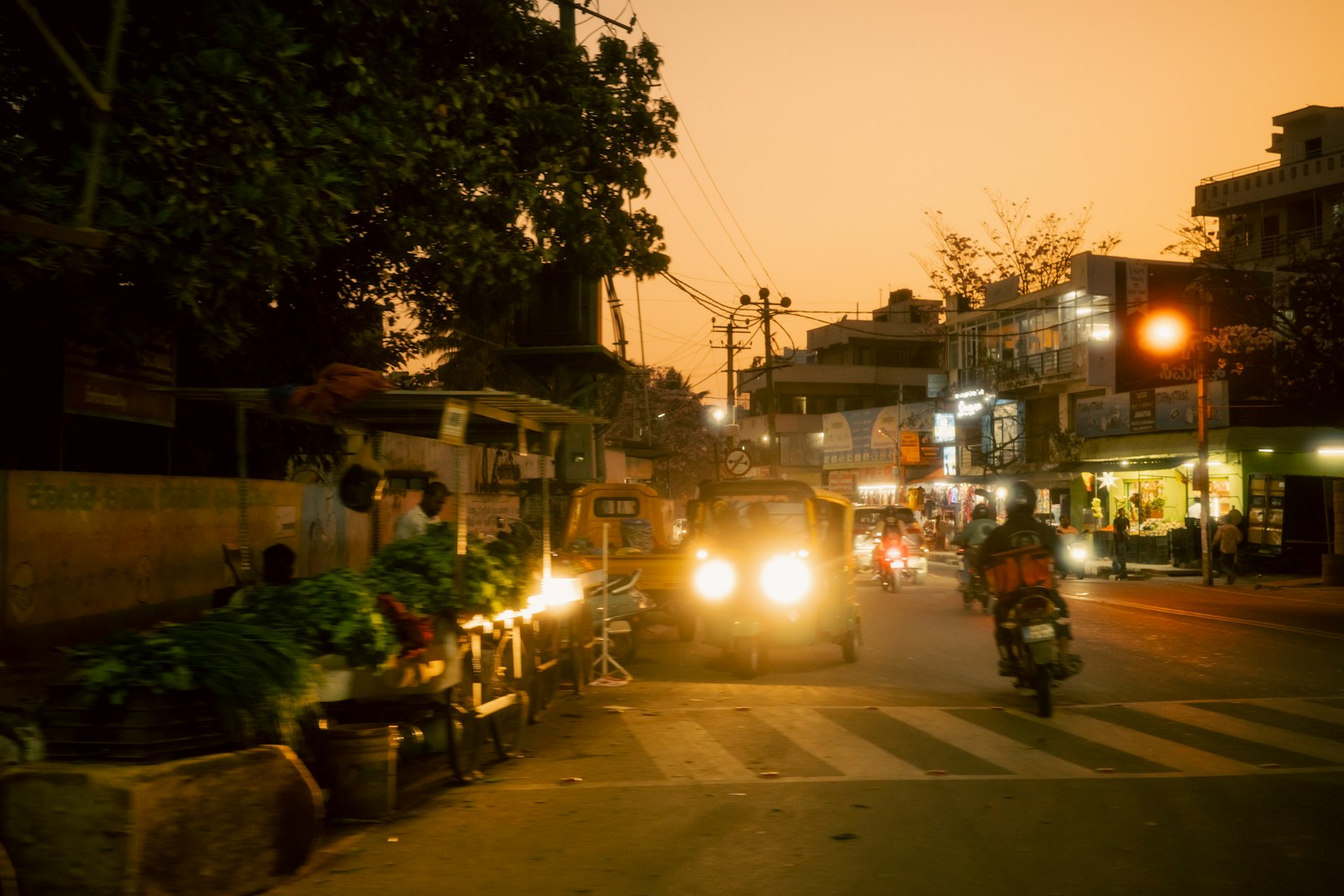 An Indian city street at dusk — autos, bikes, and everyday movement
